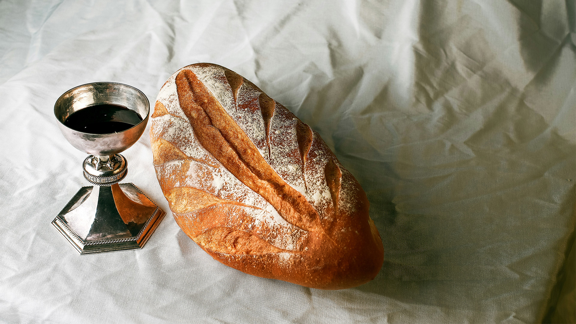 Das Foto zeigt einen gedeckten Tisch mit Brot und Wein