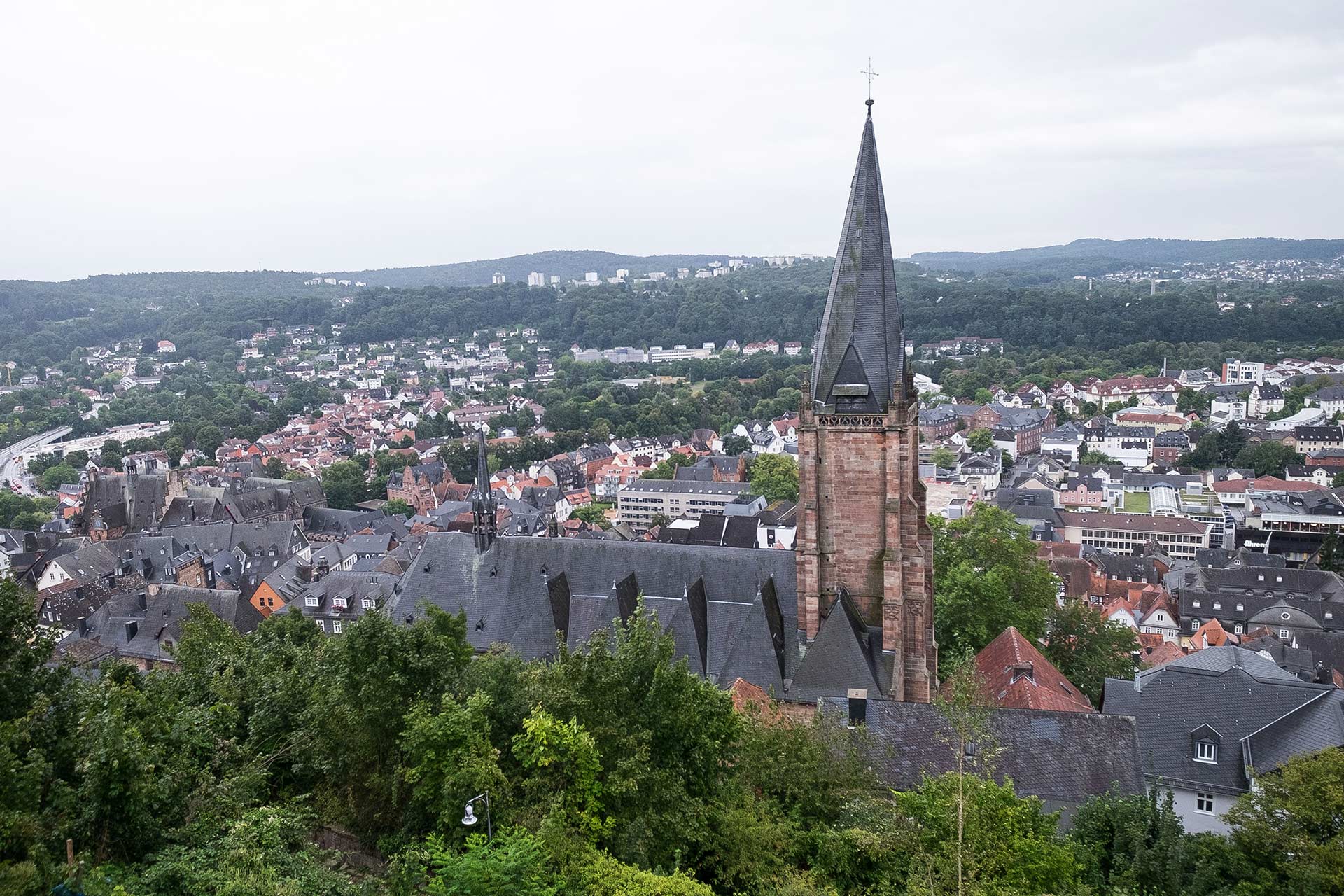 Außenaufnahme der Lutherischen Pfarrkirche in Marburg. Im Hintergrund ist die Stadt Marburg zu sehen.