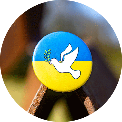 Das Foto zeigt einen Anstecker mit den Farben der Nationalflagge der Ukraine in Blau und Gelb und einer Friedenstaube